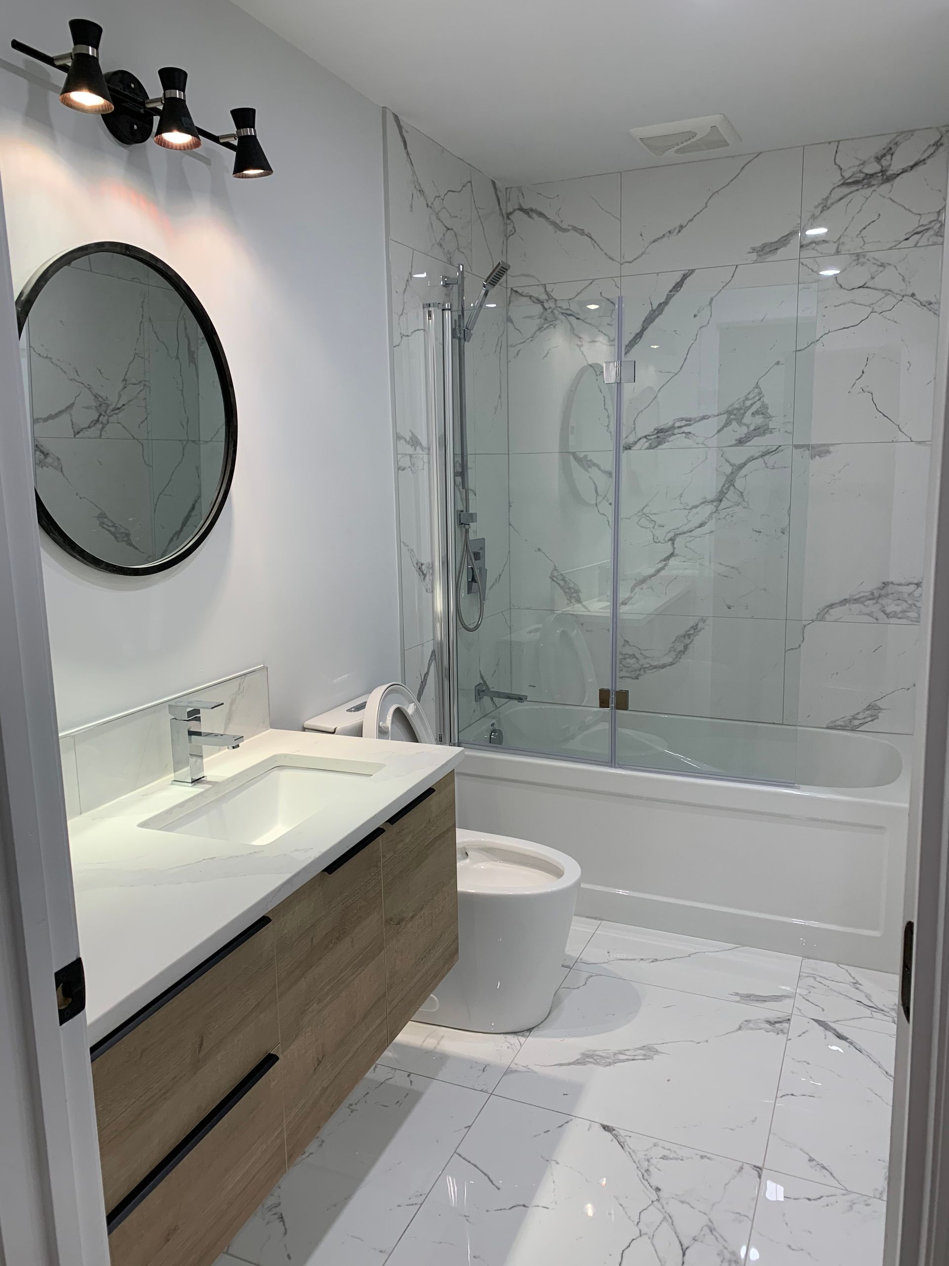 Une salle de bain avec lavabo, WC, douche et miroir.