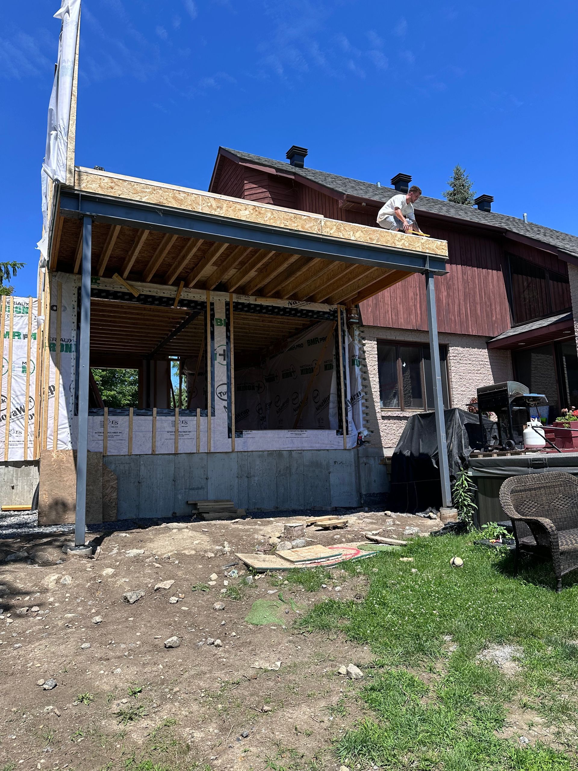 Un homme travaille sur le toit d'une maison en construction.