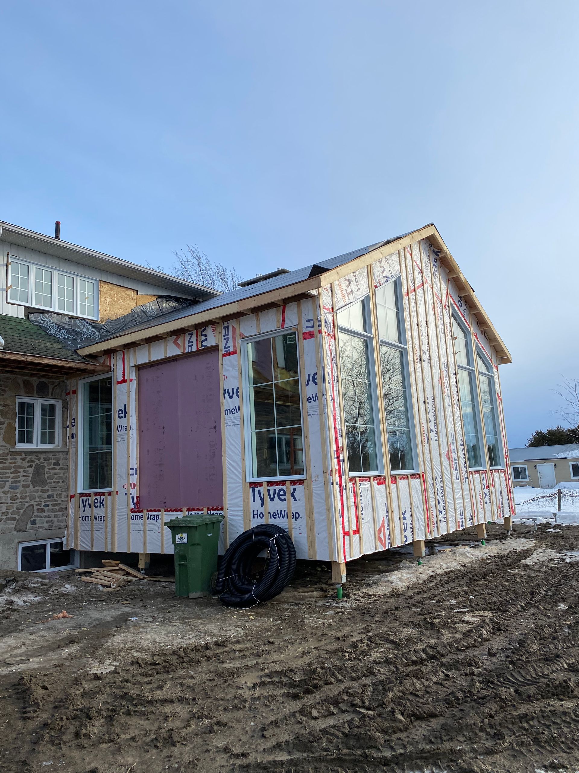 Une petite maison est en construction au milieu d'un champ de terre.