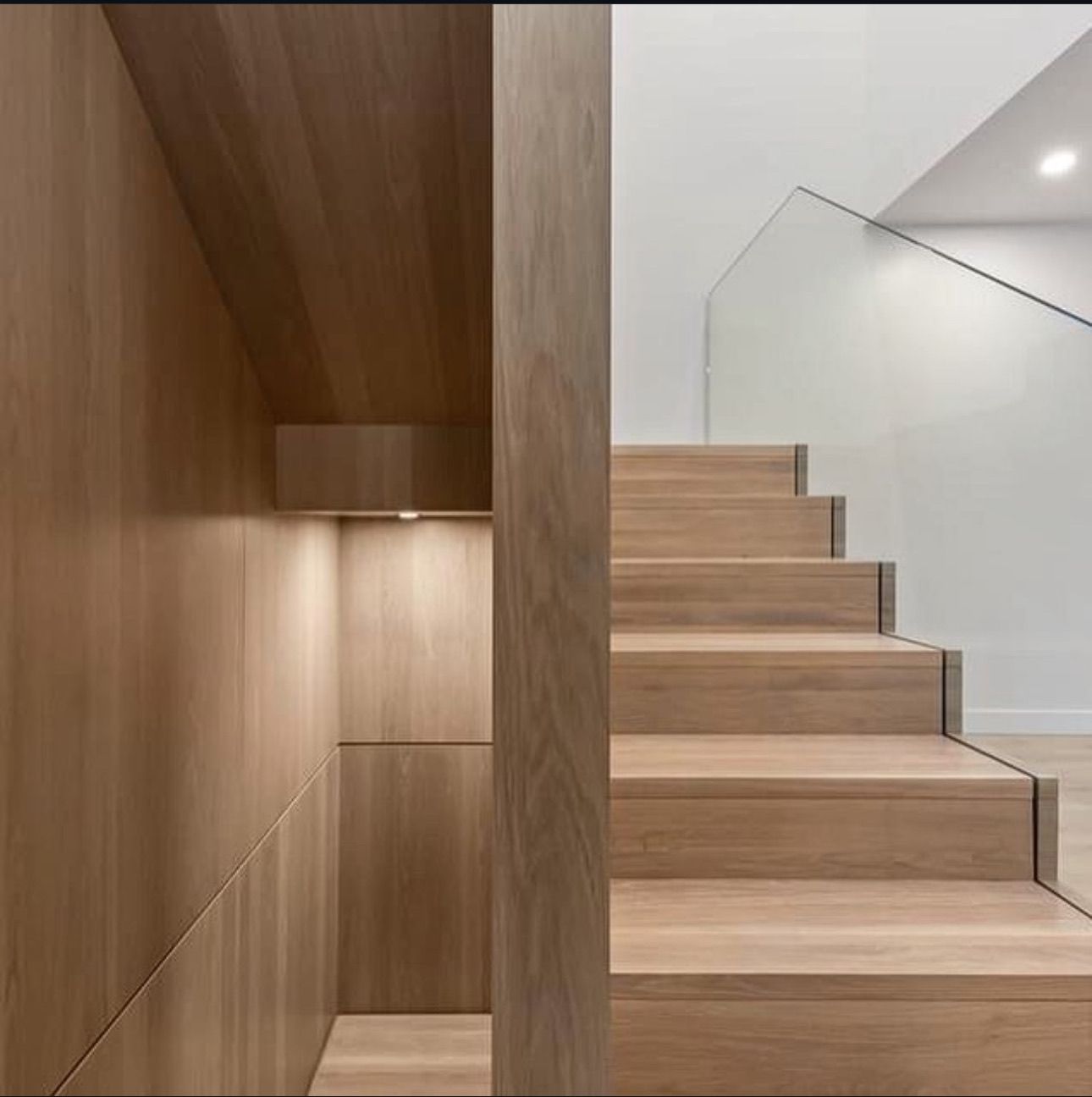 Un escalier en bois avec une rampe en verre dans une maison
