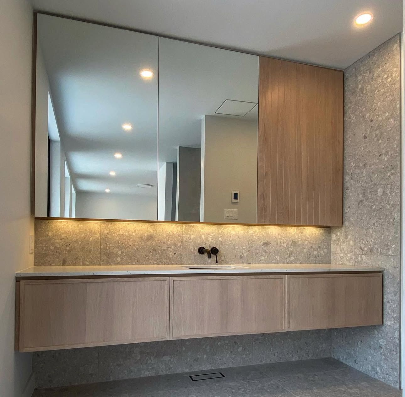 Une salle de bain avec un grand miroir et un lavabo