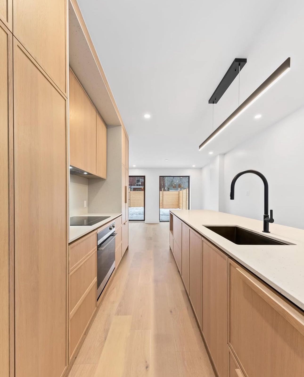 Une longue cuisine avec des armoires en bois et un évier.