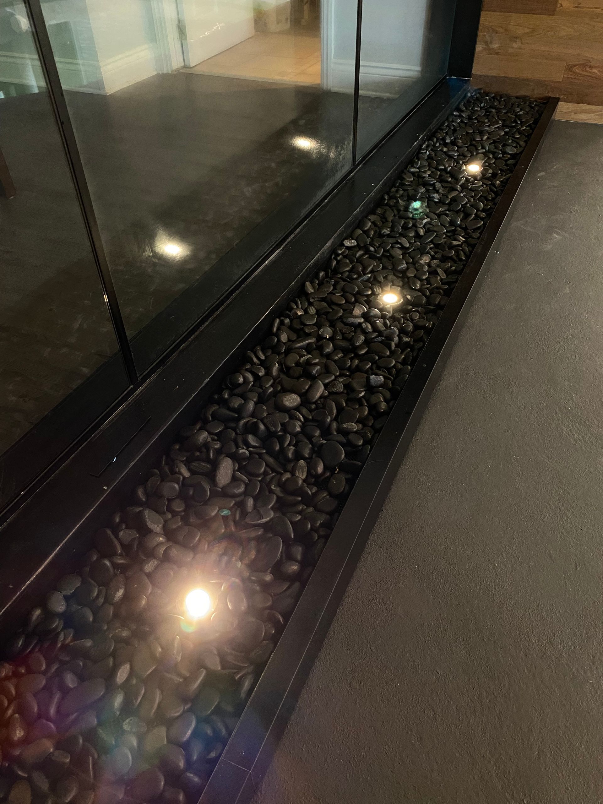 Une rangée de rochers noirs assis à côté d'un mur de verre.
