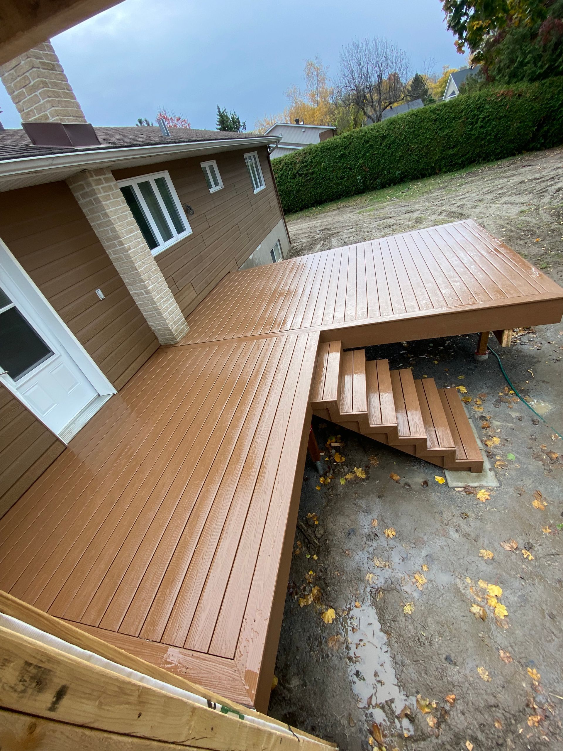 Une terrasse en bois avec des escaliers qui y mènent devant une maison.