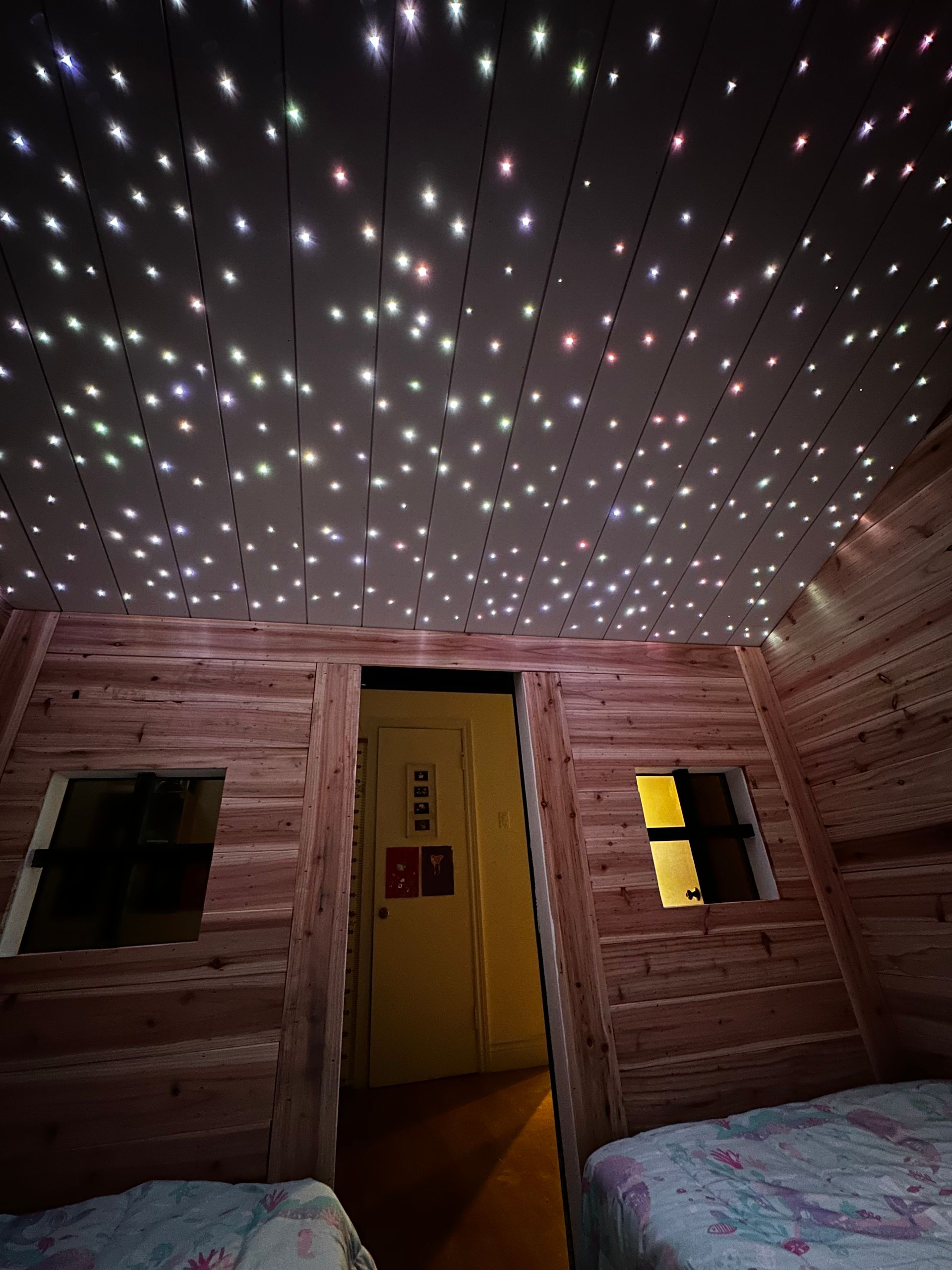 Une chambre avec deux lits et un plafond qui ressemble à un ciel étoilé.