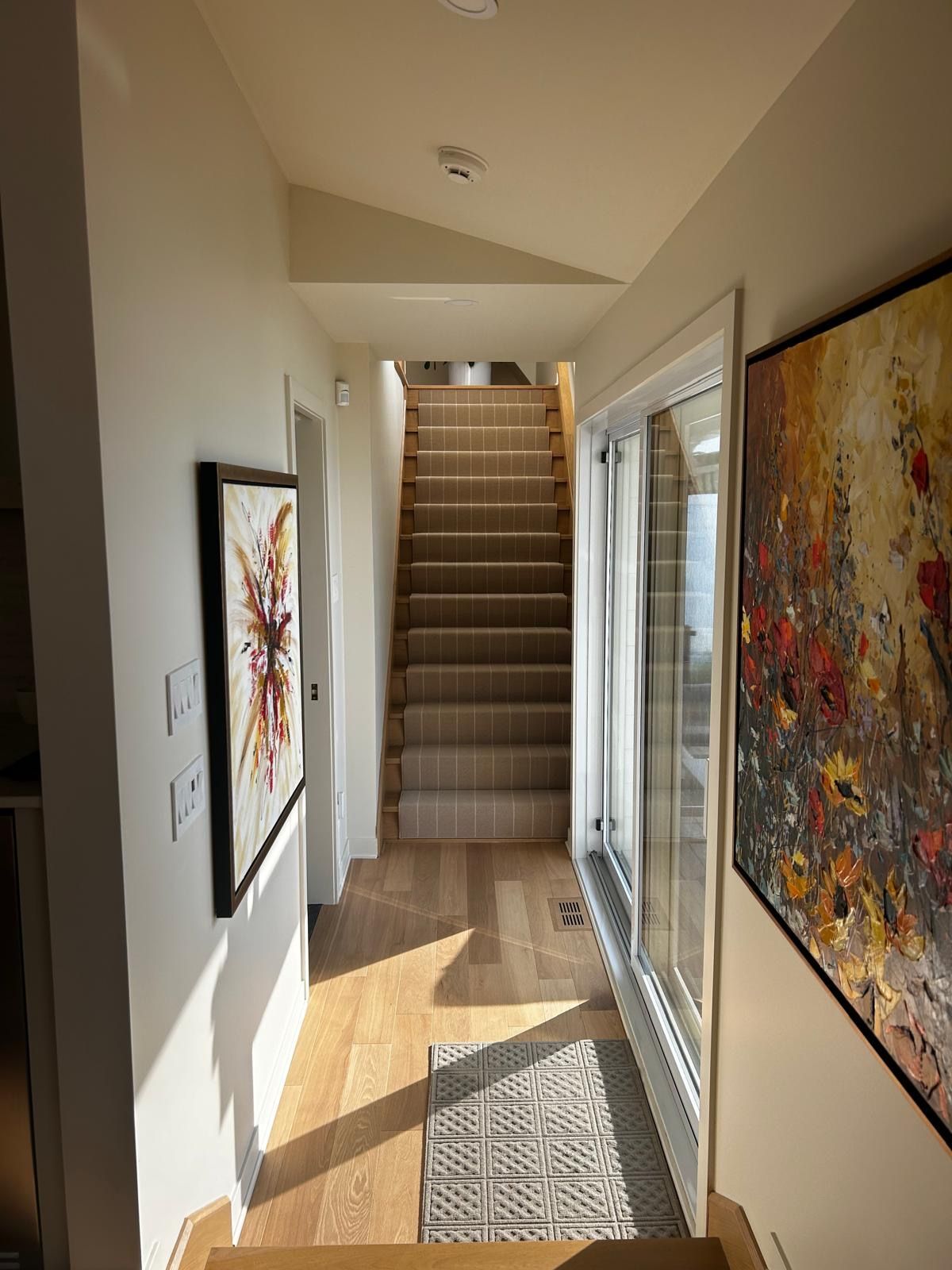 Un couloir avec des escaliers et un tableau sur le mur.