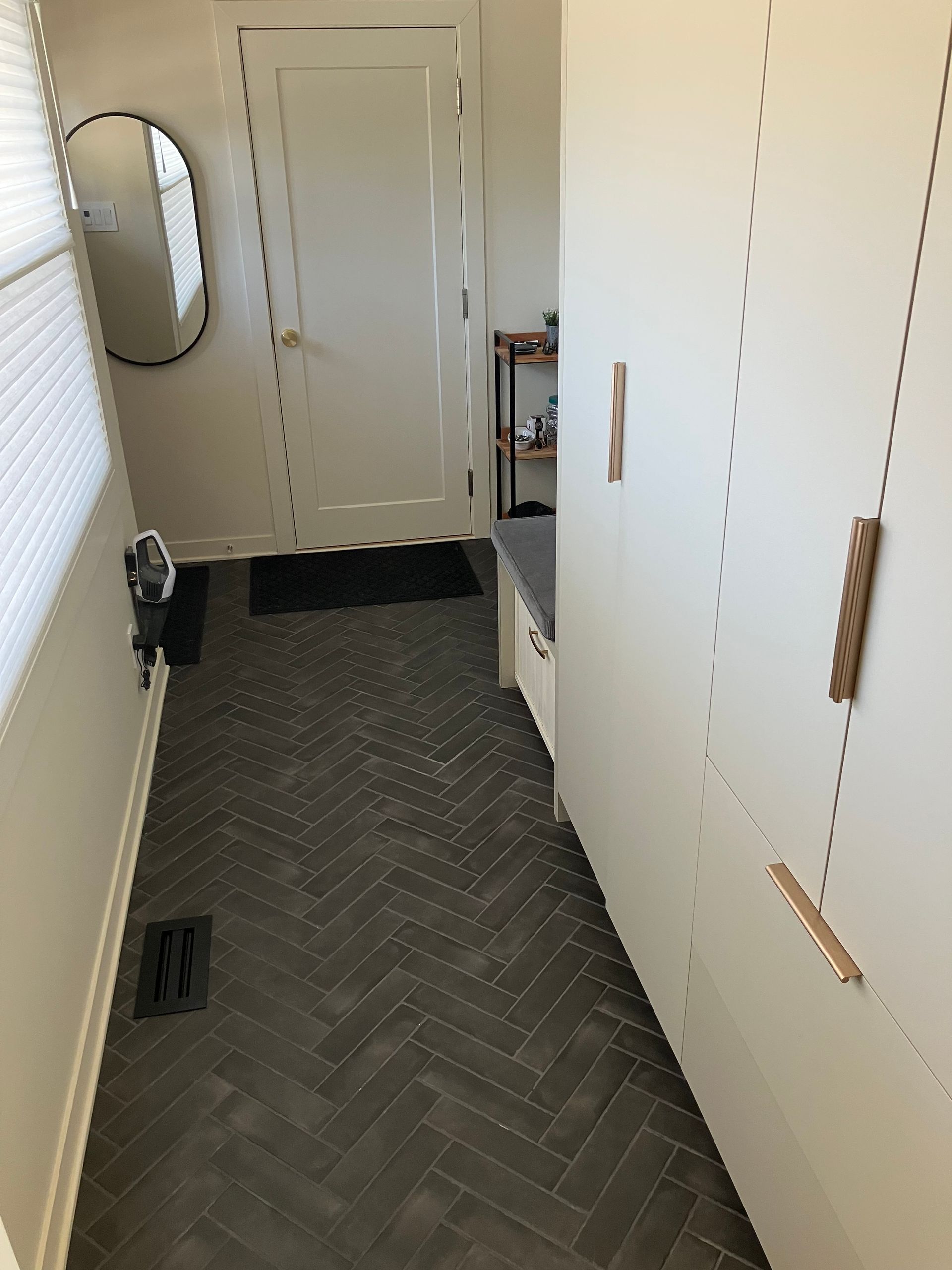 Un couloir avec un sol à chevrons et un miroir au mur