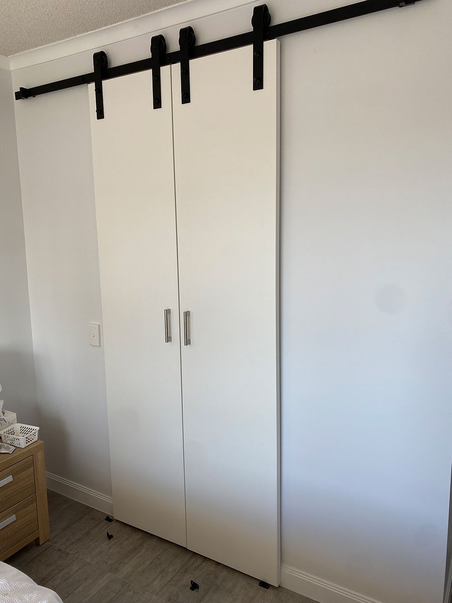 A Bedroom With Sliding Barn Doors And A Bed — Cut N Edge Panel Factory In Coolum Beach, QLD