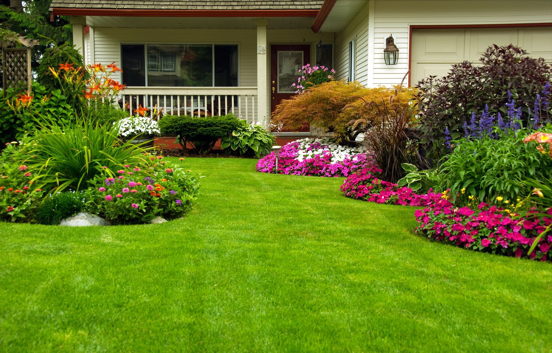 Immaculately manicured spring-summer residential yard featuring lush green lawns, vibrant flower beds, and neatly trimmed hedges.