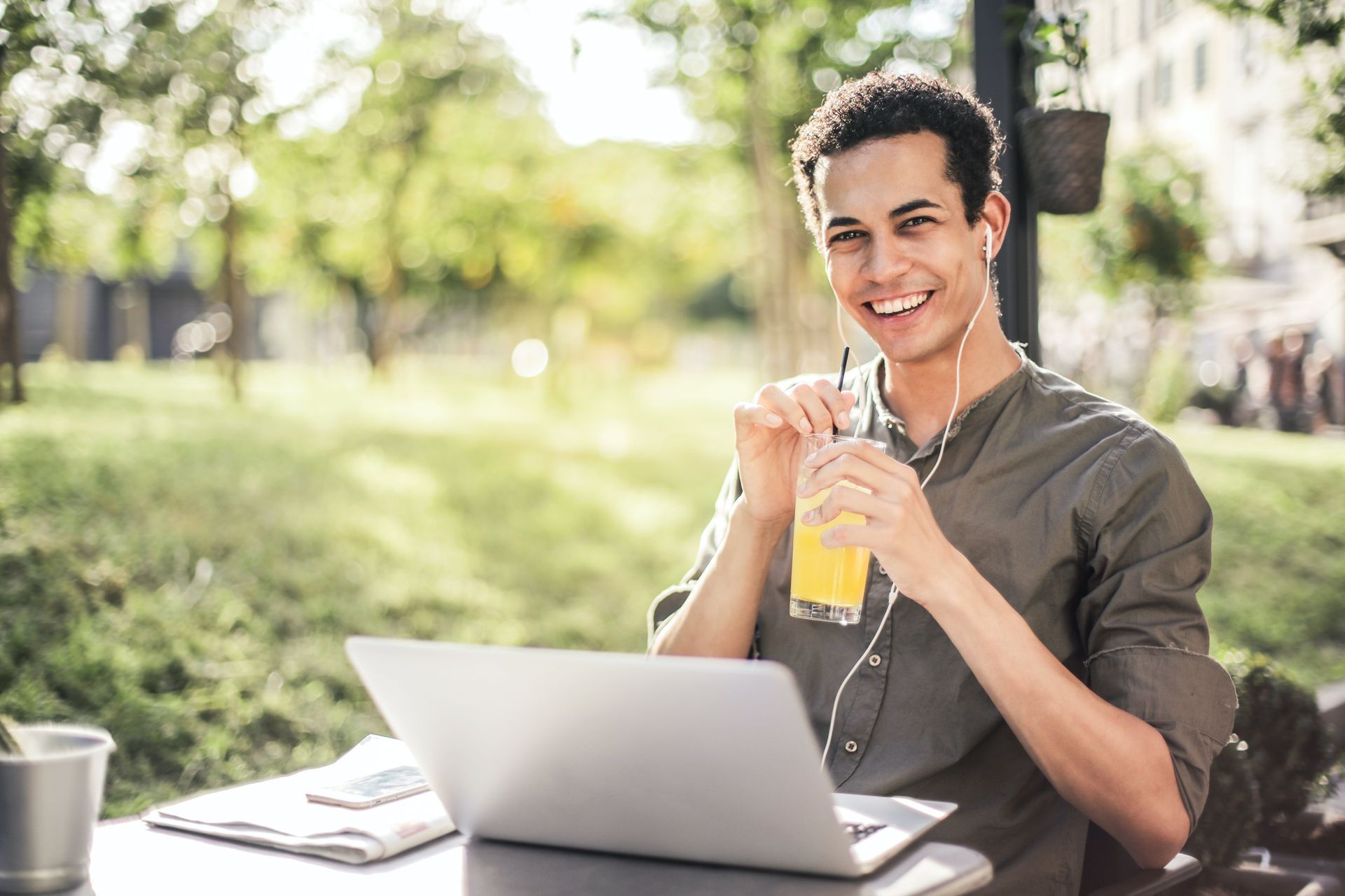 a man is sitting at a table with a laptop and drinking orange juice .