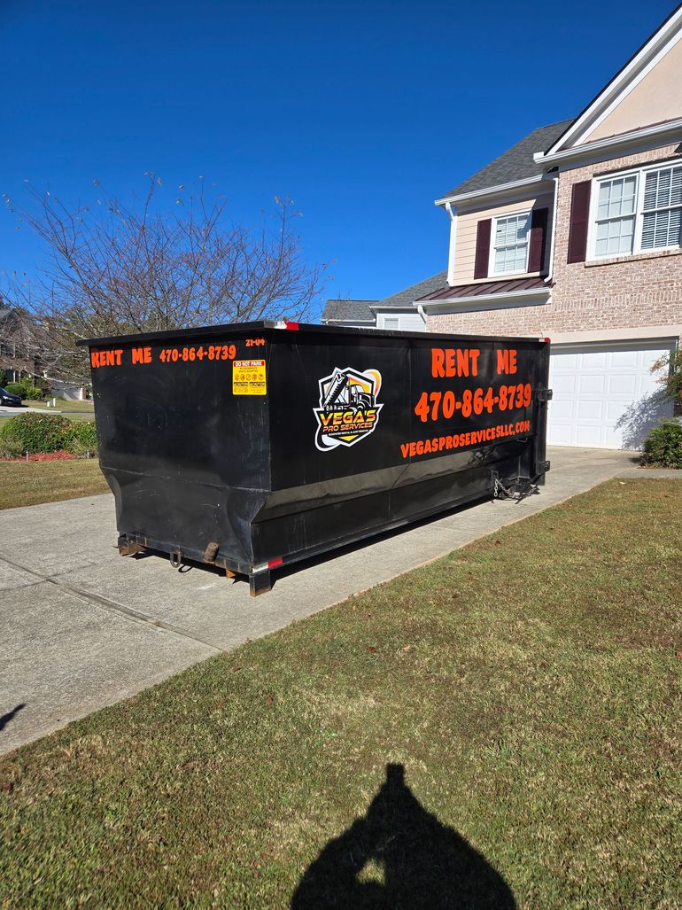 Black dumpster in a driveway with