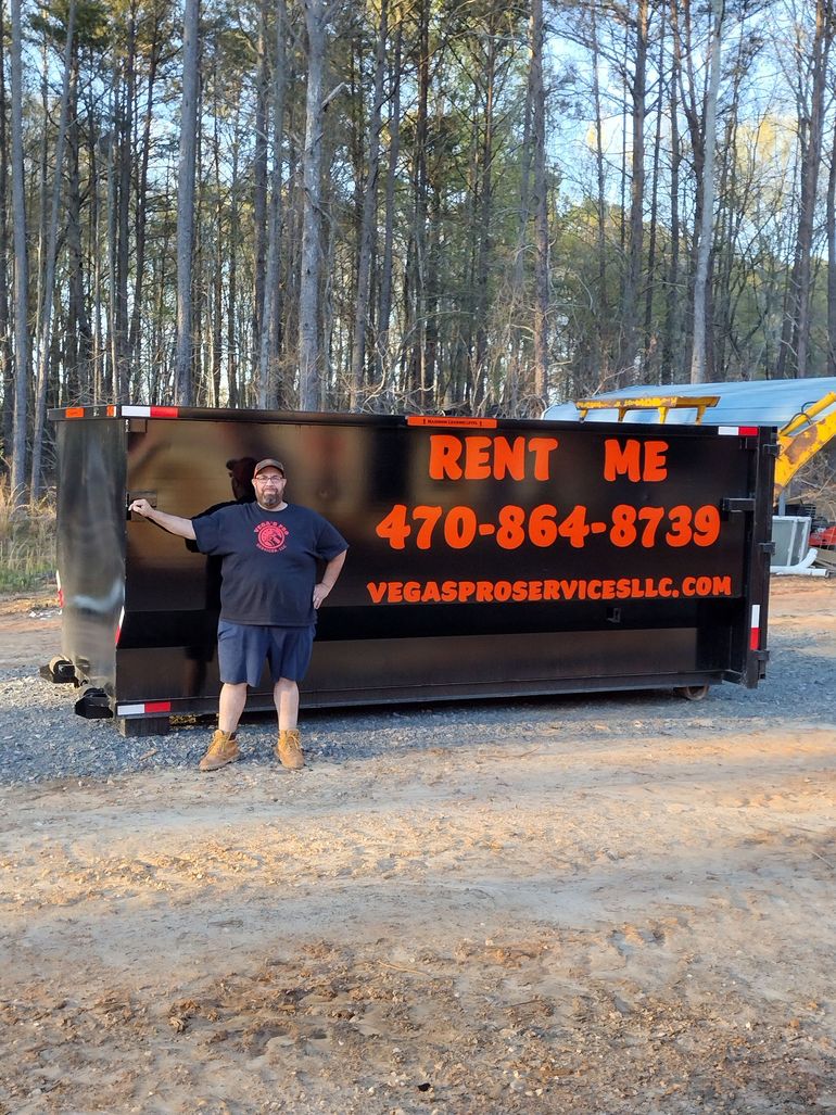 Man standing beside a black dumpster with