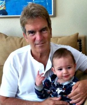 Man in white shirt holding a smiling baby on a couch