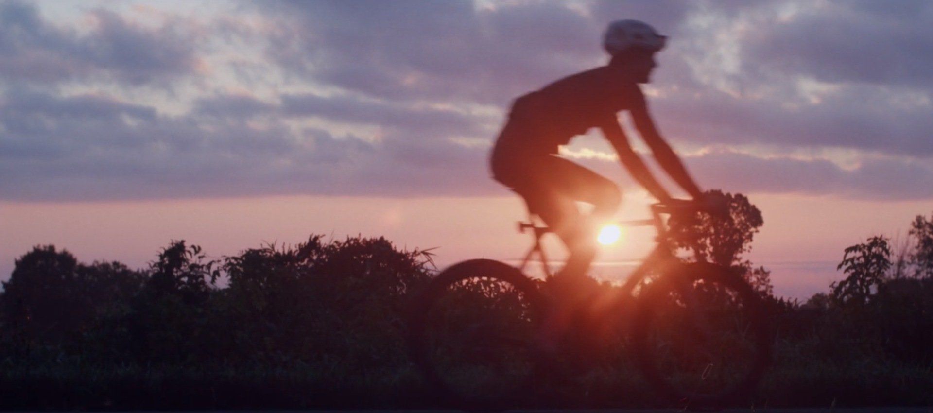 A person is riding a bike at sunset.