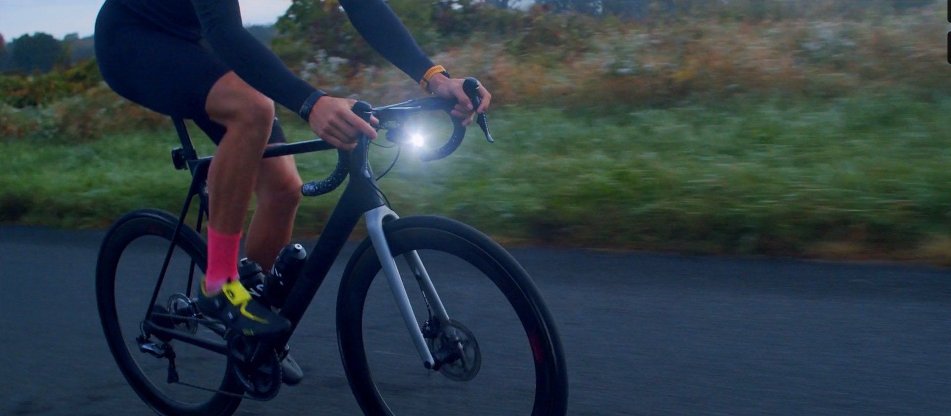 A person is riding a bike on a road at night.