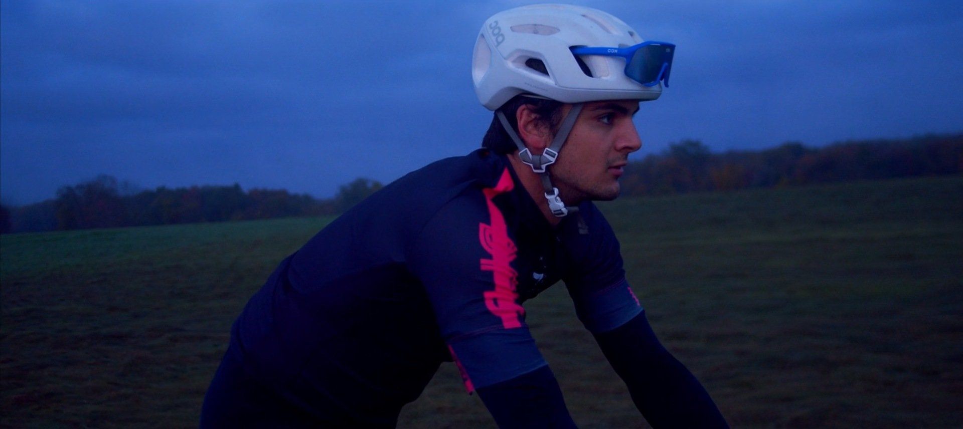 A man wearing a helmet and goggles is riding a bike in a field.