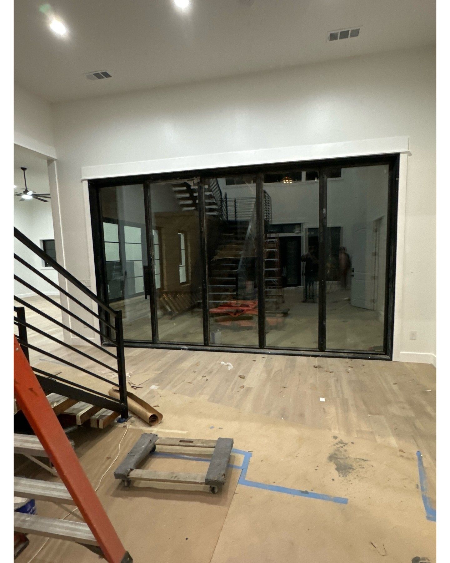 An unfinished room with white drywall, a window on the left, and exposed floor edges.