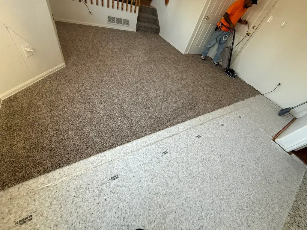 Carpeted hallway with stairs and a person in an orange shirt near the right wall