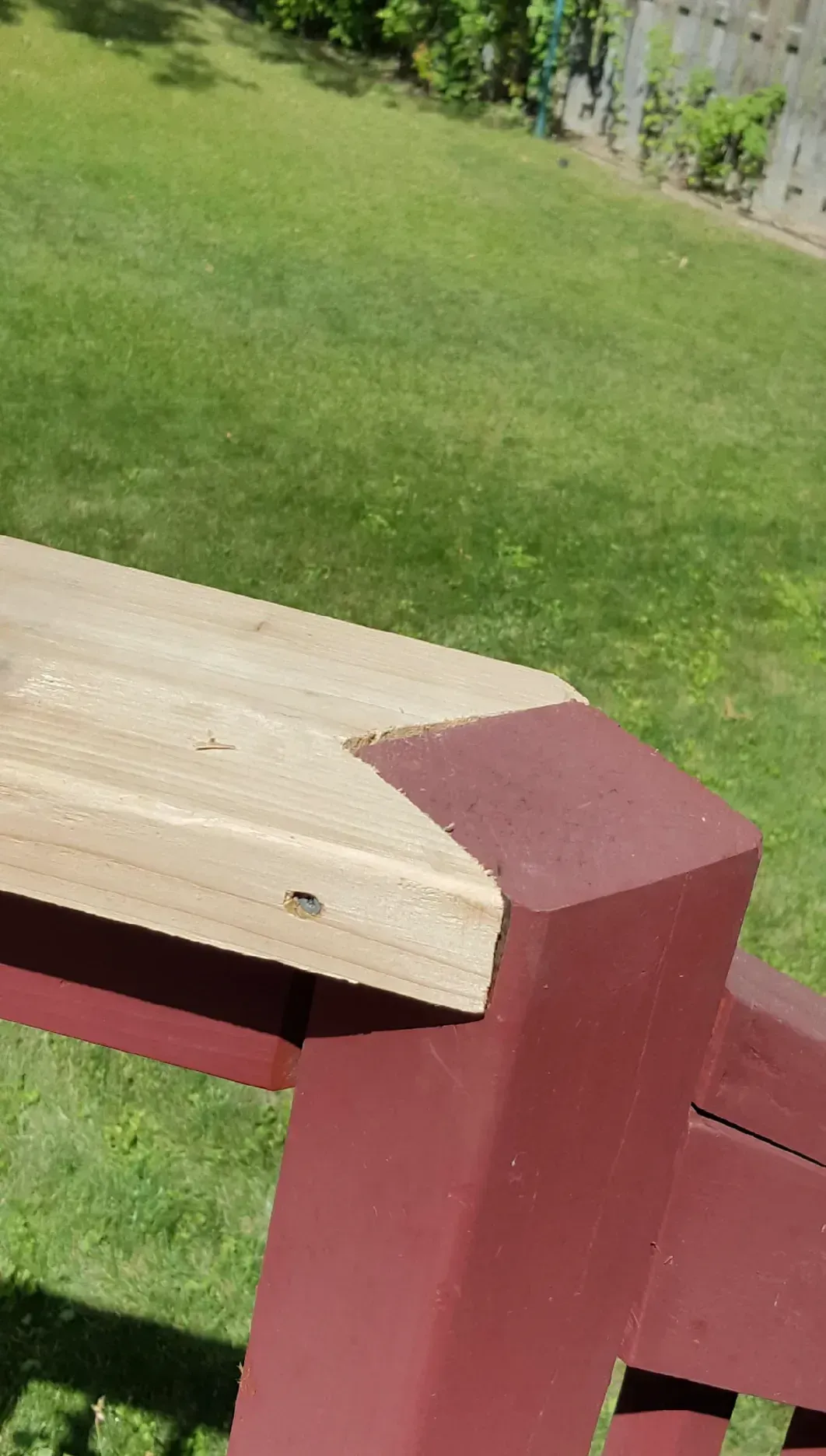 Wooden deck railing with a red post beside a green lawn outdoors