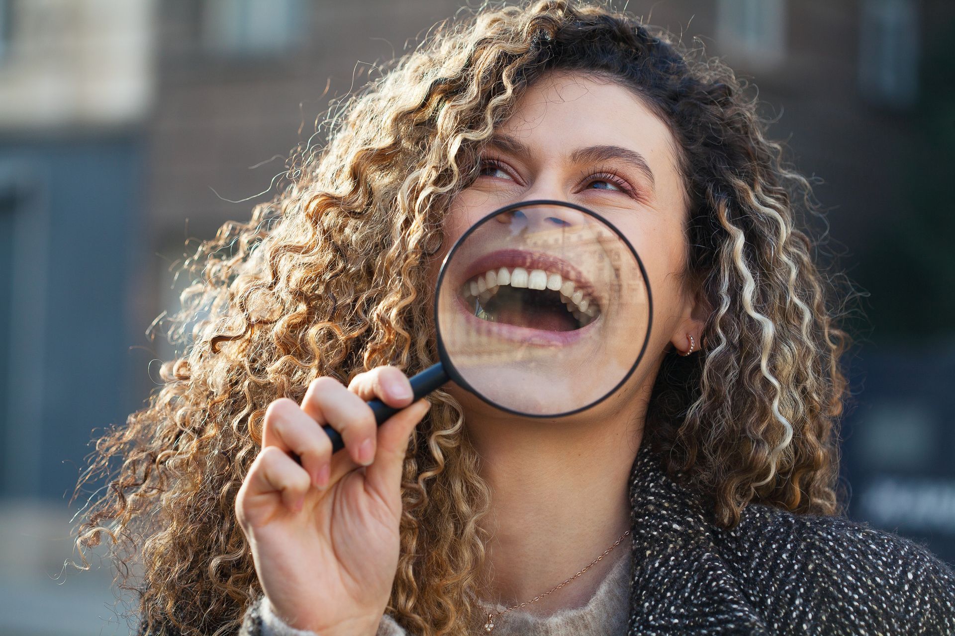 Young woman holding magnifying glass in front of her smile Young woman holding magnifying glass in front of her smile