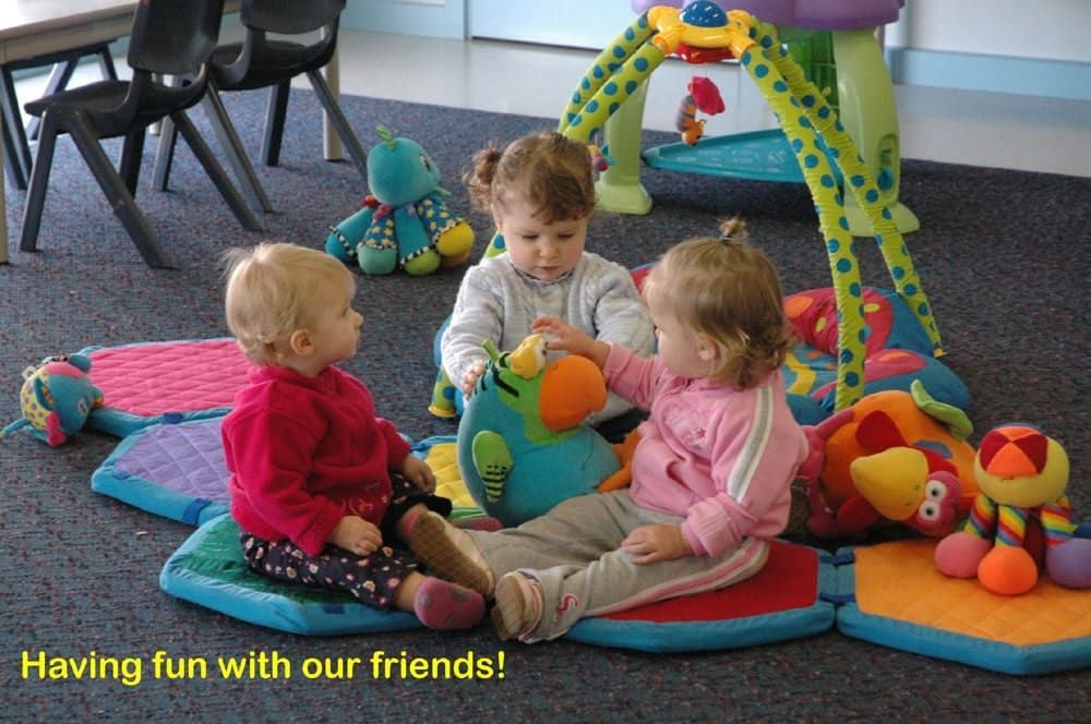 Three little girls are sitting on the floor playing with stuffed animals ..