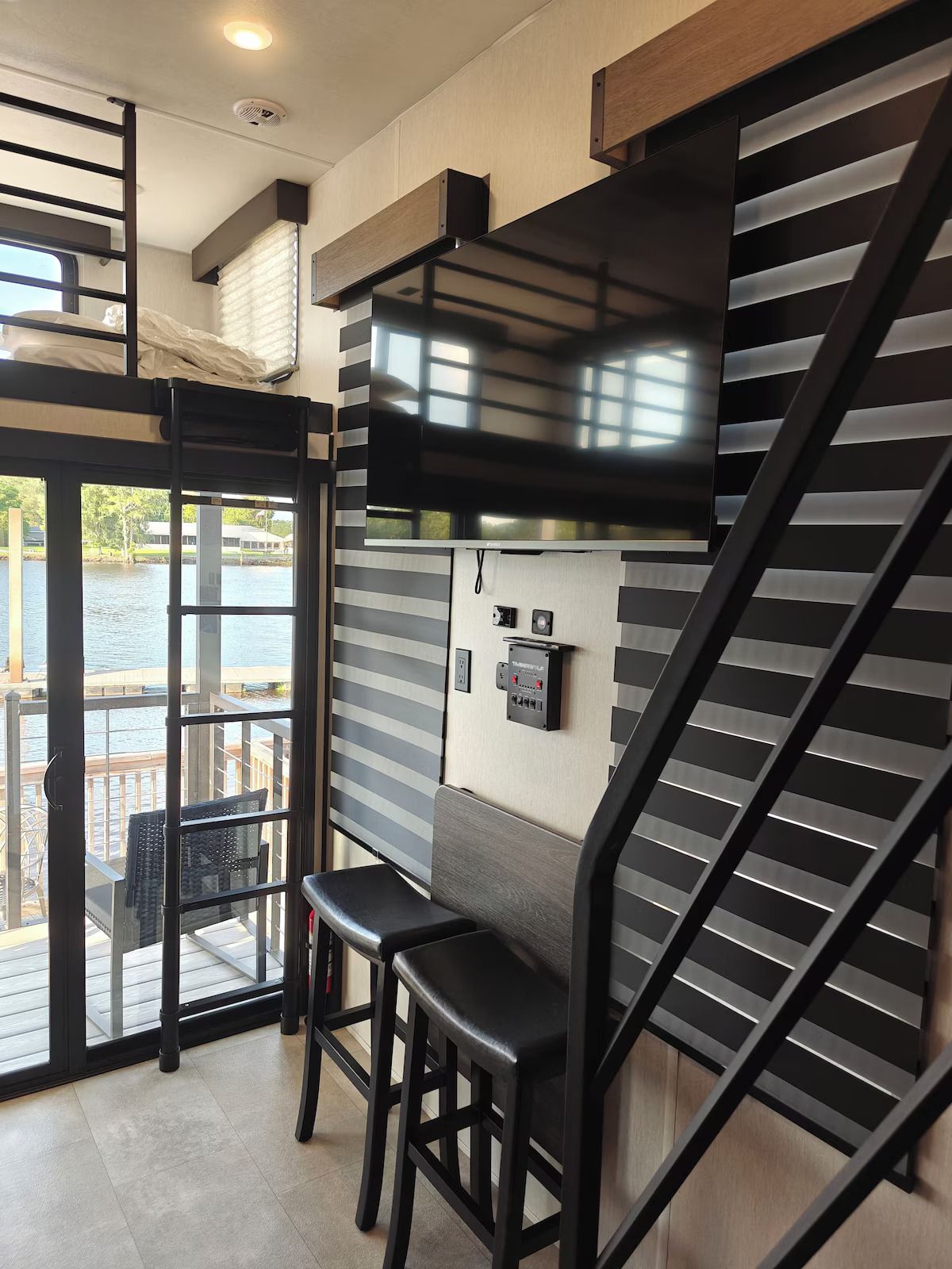 A living room with a staircase and a flat screen tv