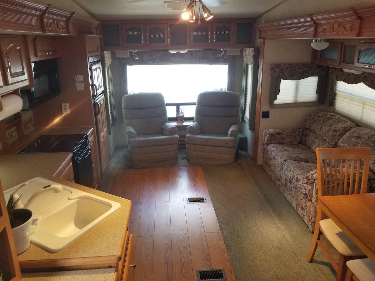 The inside of a rv with a couch and chairs