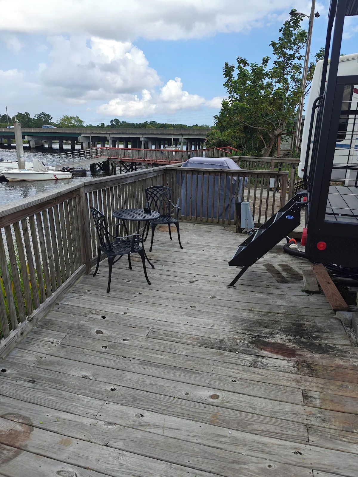 A wooden deck with a table and chairs on it next to a body of water.
