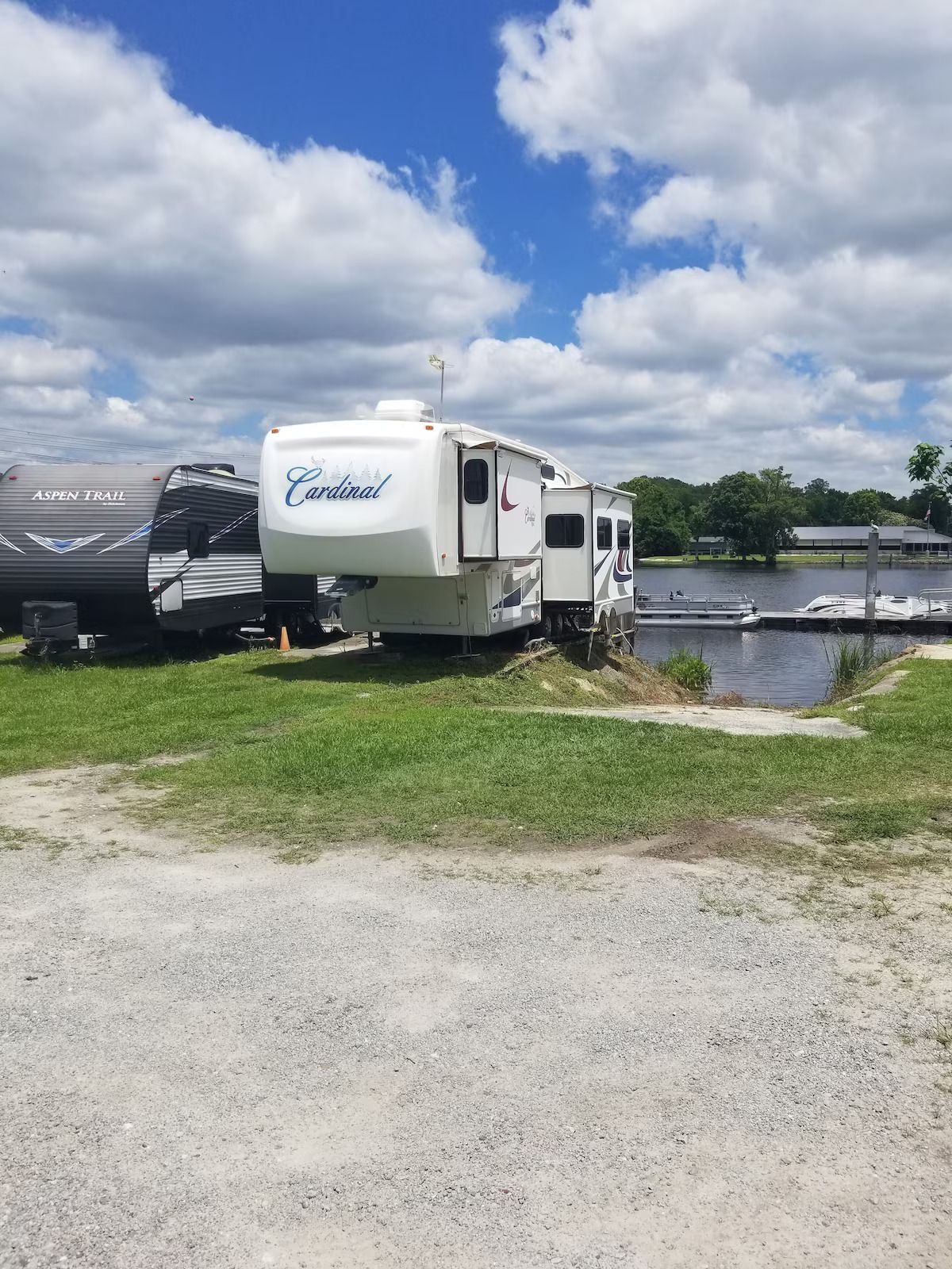 A white rv is parked in a grassy area next to a body of water.