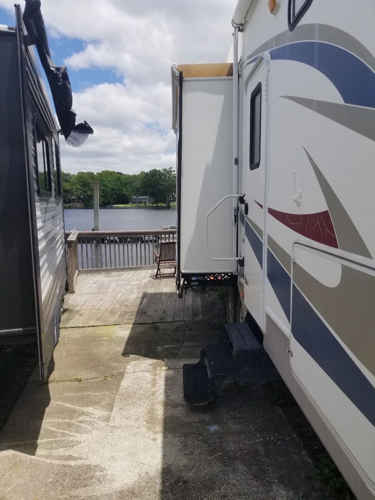 A rv is parked next to another rv on a dock.