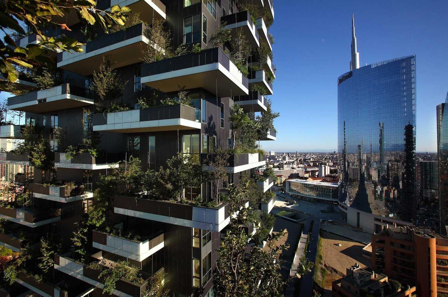 Moderni balconi di grattacieli ricoperti di verde accanto a un grattacielo di vetro riflettente nello skyline cittadino