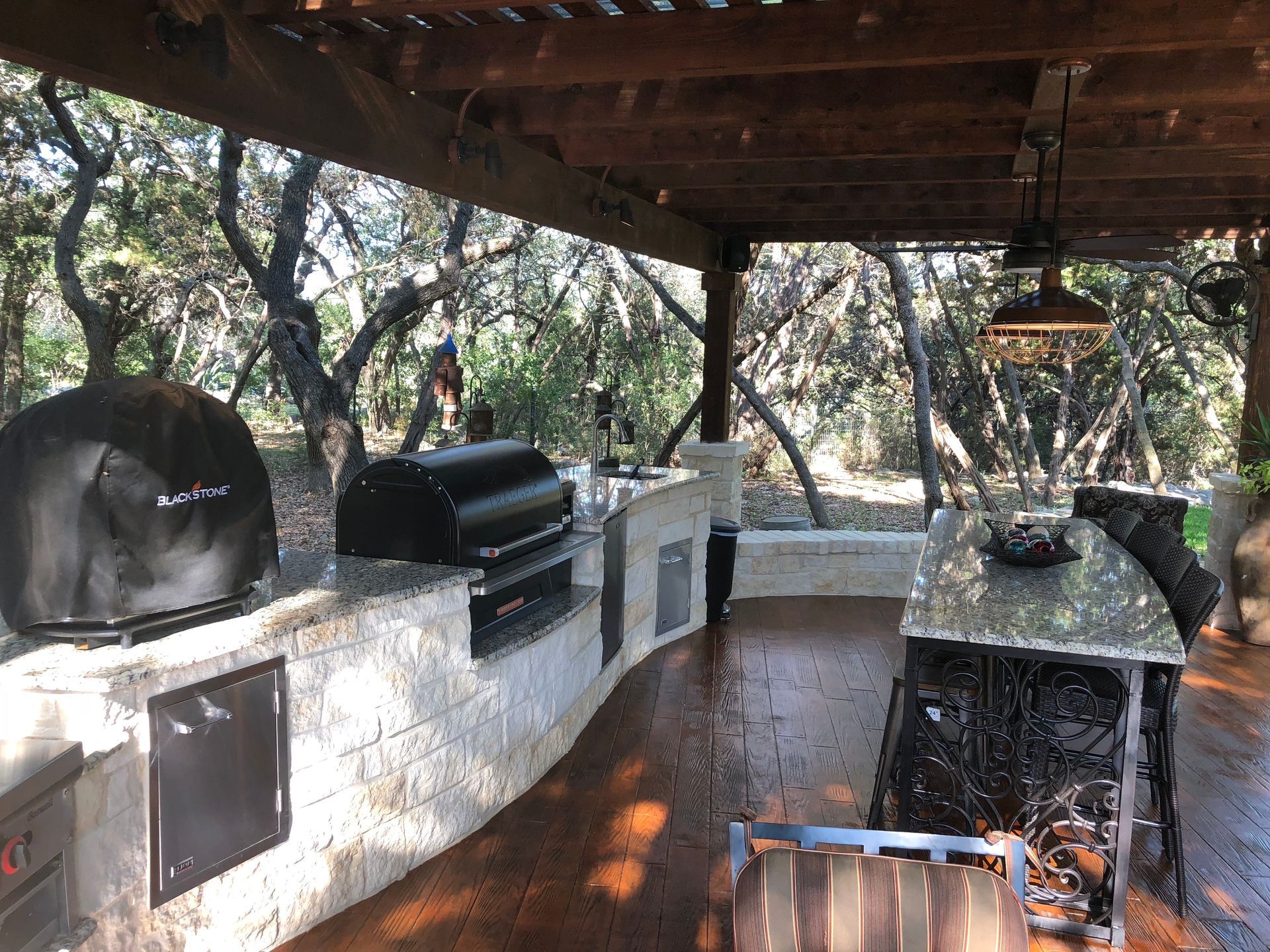 An outdoor kitchen with a pizza oven and a grill built by Fine Patio Design San Antonio TX