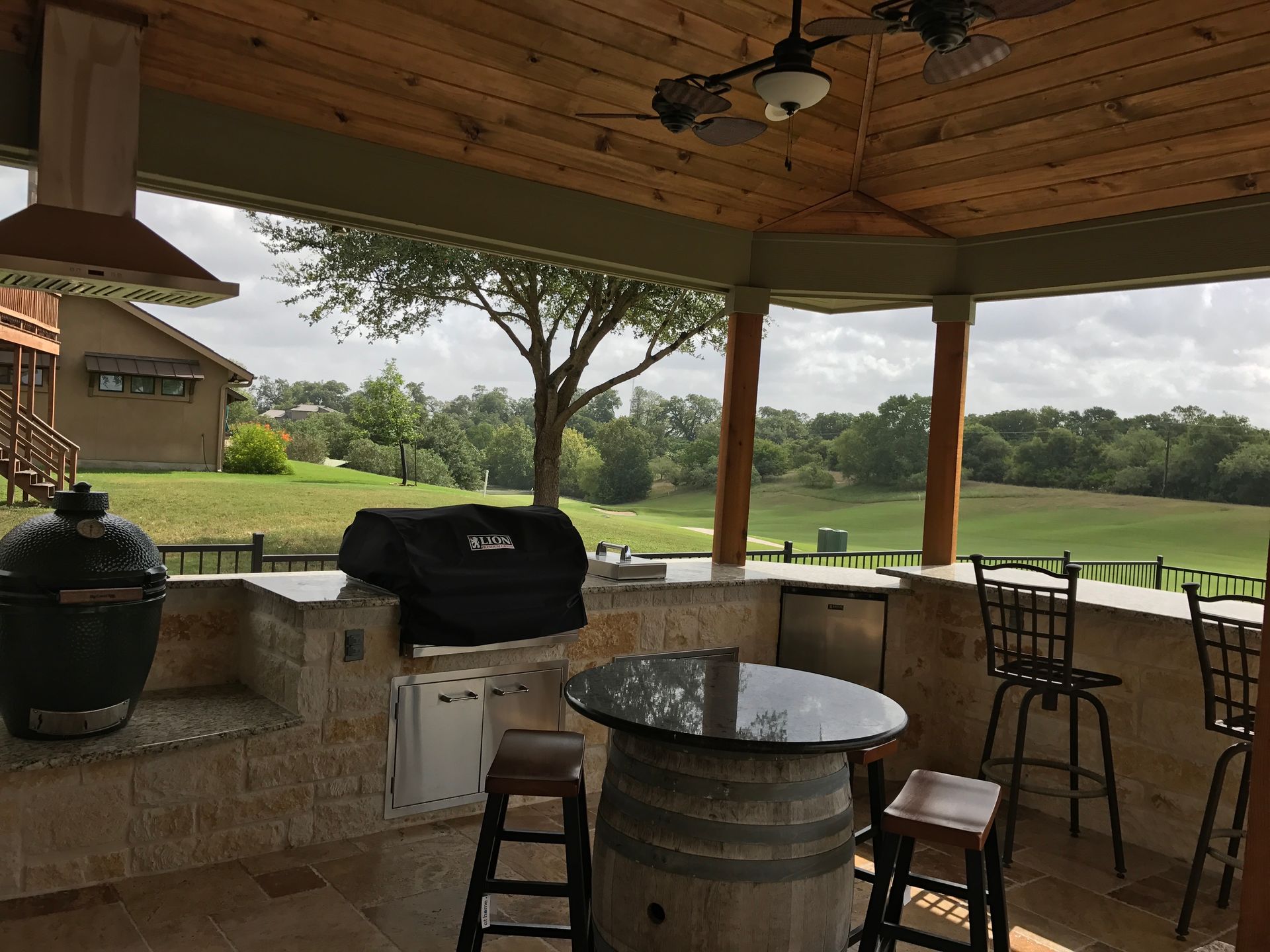 A patio area with a grill and a table with a view of a golf course built by Fine Patio Design San Antonio TX