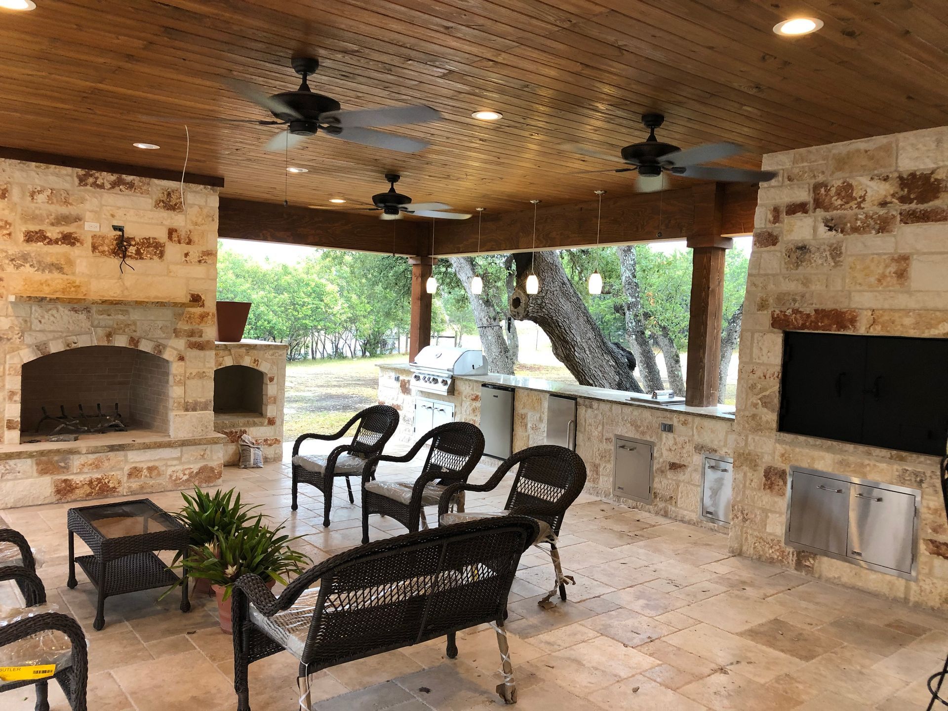 A patio with a fireplace and ceiling fans built by Fine Patio Design San Antonio TX 