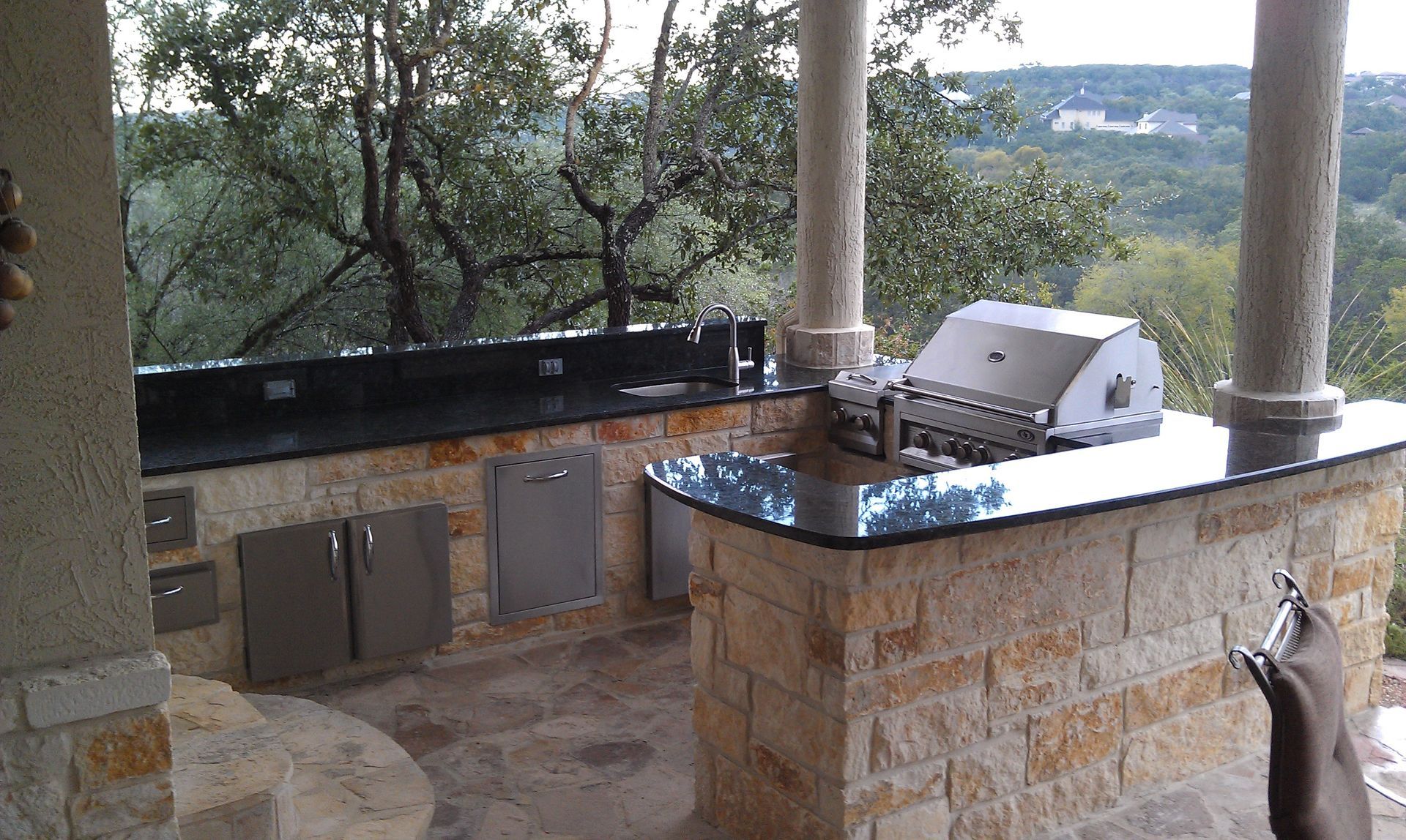 An outdoor kitchen with a view of a forest built by Fine Patio Design San Antonio TX