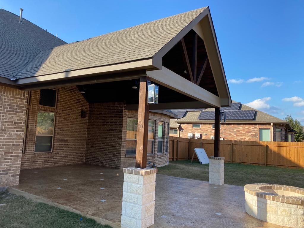 A brick house with a covered patio and a fire pit built by Fine Patio Design San Antonio TX