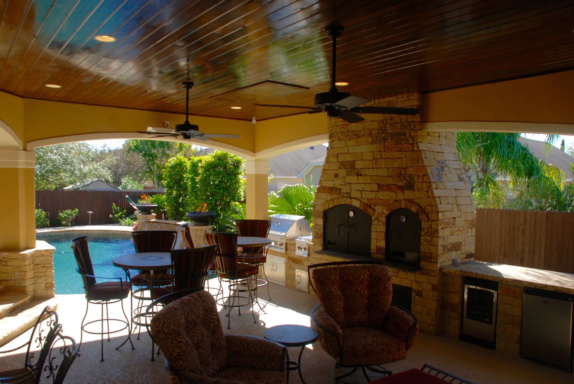 A patio with a fireplace and a ceiling fan built by Fine Patio Design San Antonio TX