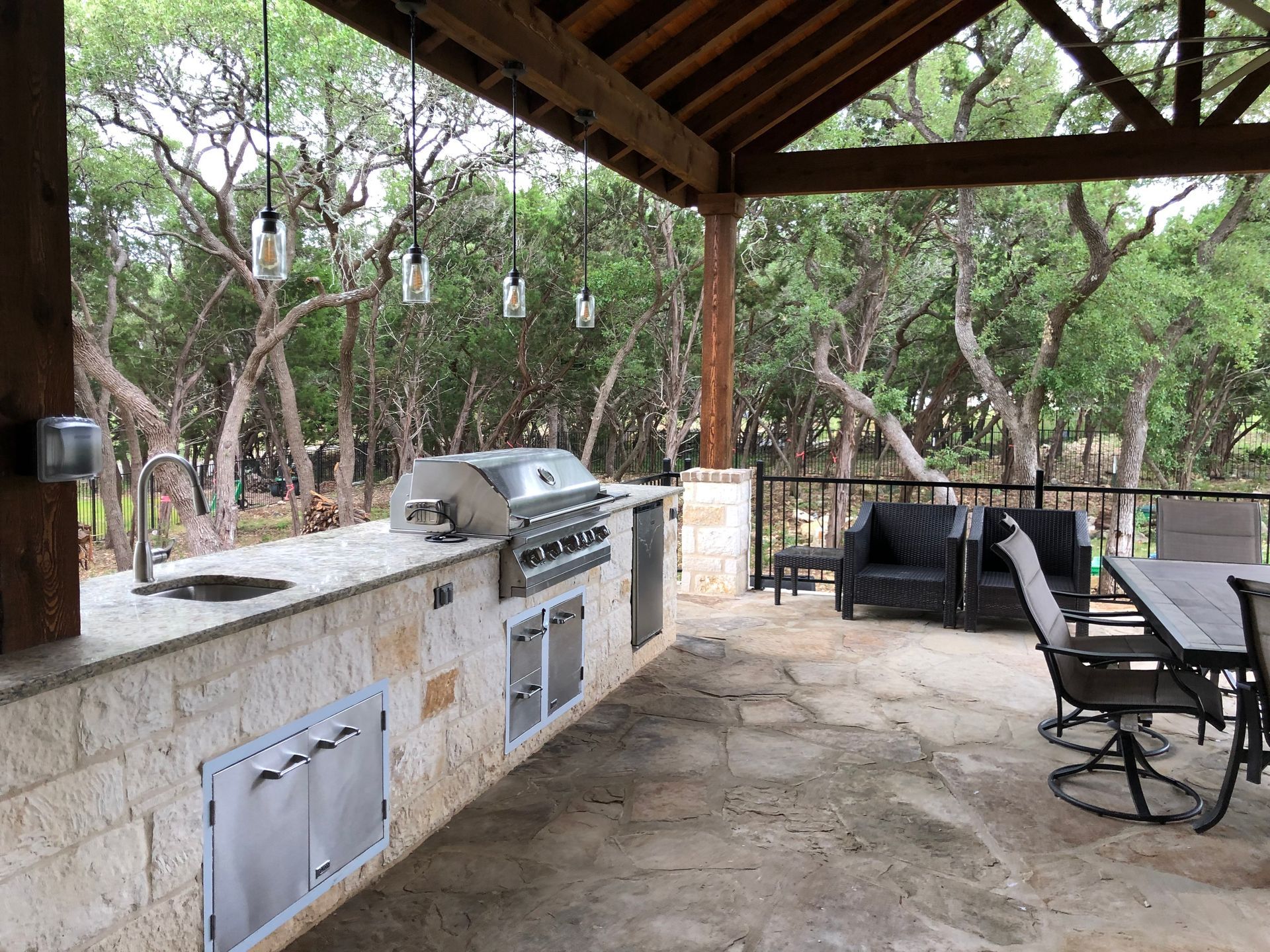 A covered patio with a table and chairs and a grill built by Fine Patio Design San Antonio TX