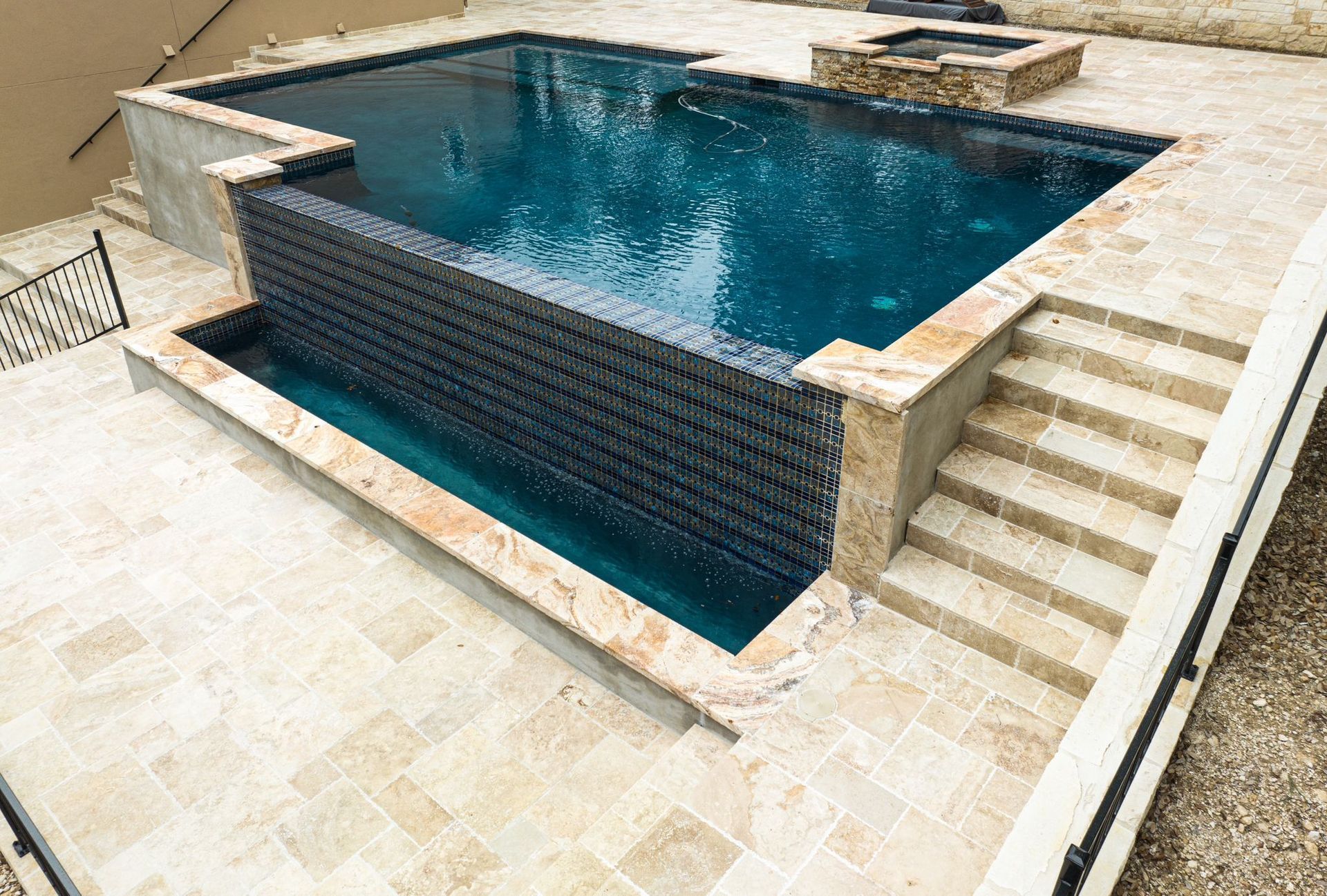 A large swimming pool with stairs leading up to it built by Fine Patio Design San Antonio TX