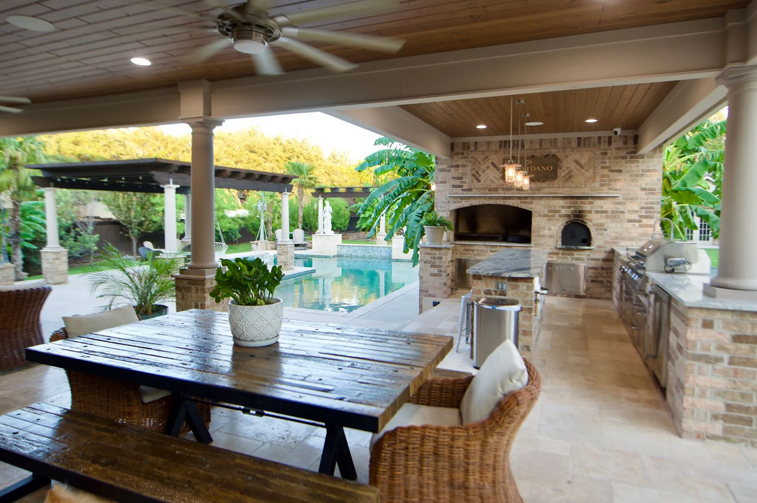 A patio with a table and chairs and a ceiling fan built by Fine Patio Design San Antonio TX