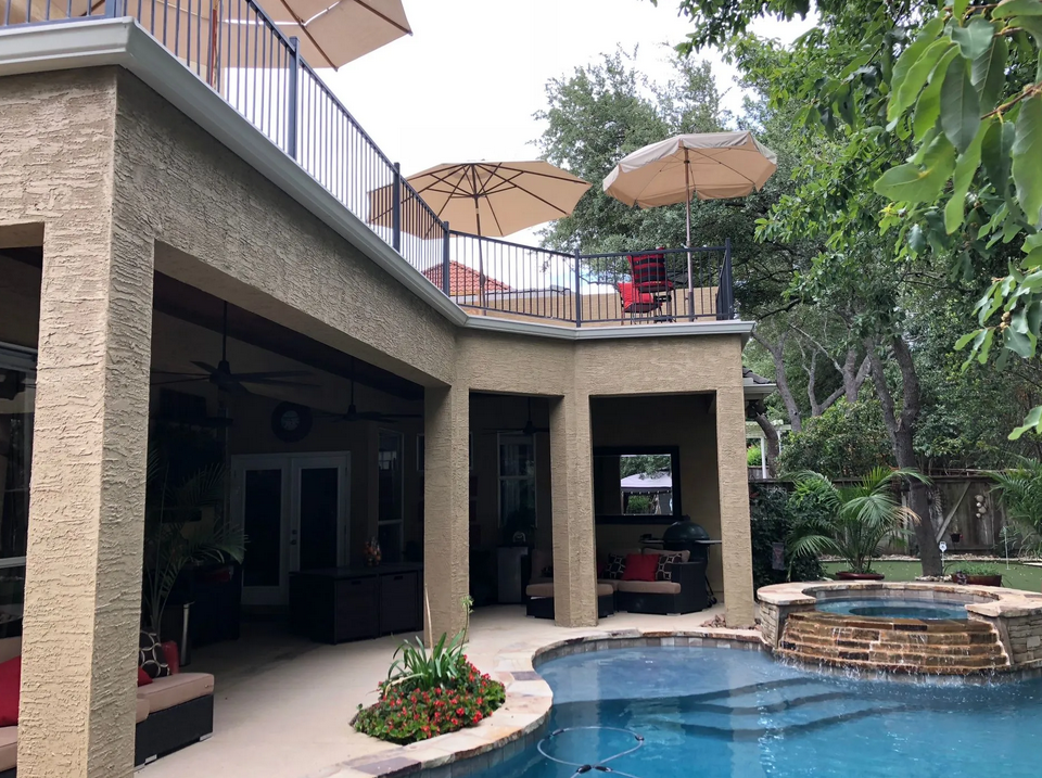 A large swimming pool with umbrellas on top of it built by Fine Patio Design San Antonio TX