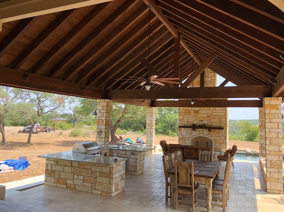 A patio with a table and chairs under a wooden roof built by Fine Patio Design San Antonio TX