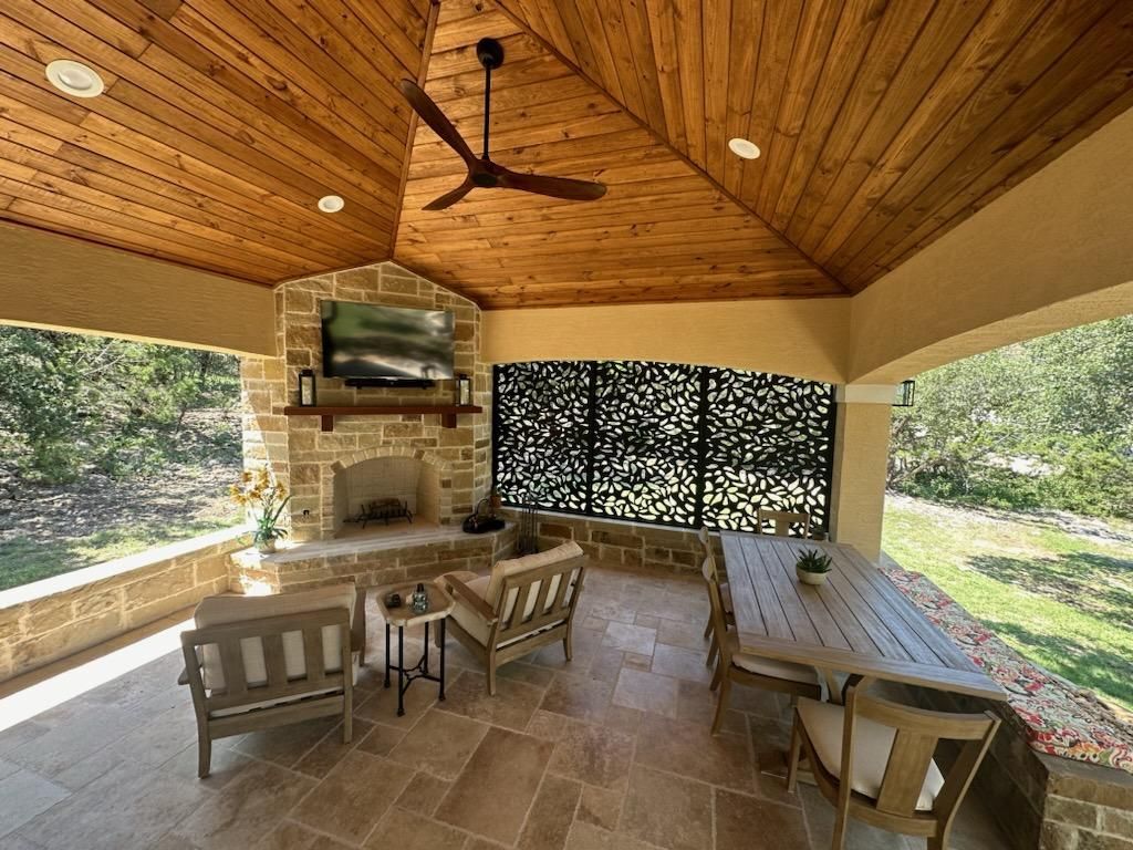 A patio with a ceiling fan and a fireplace built by Fine Patio Design San Antonio TX