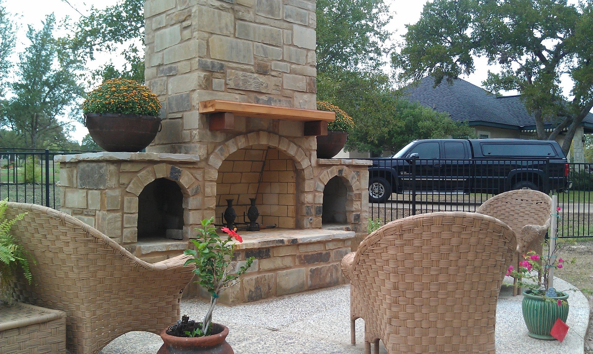 A black van is parked in front of a stone fireplace built by Fine Patio Design San Antonio TX