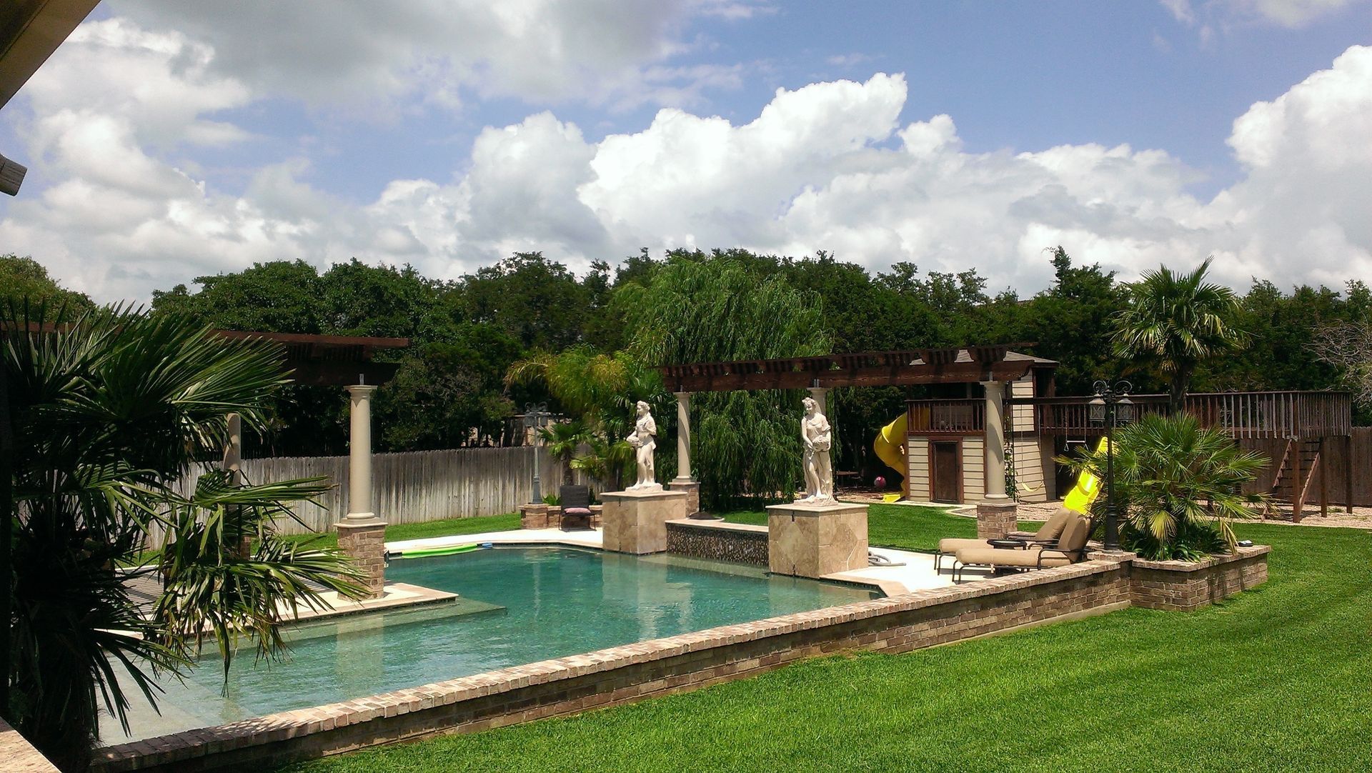 A large backyard with a swimming pool and a slide built by Fine Patio Design San Antonio TX