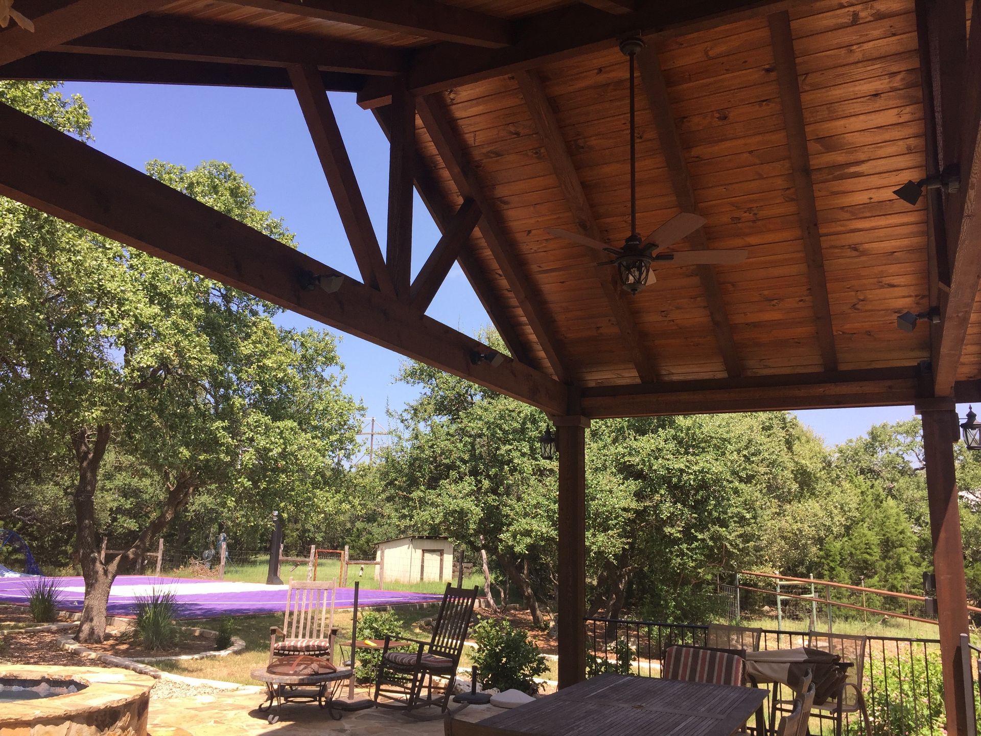 A ceiling fan hangs from the roof of a wooden structure built by Fine Patio Design San Antonio TX
