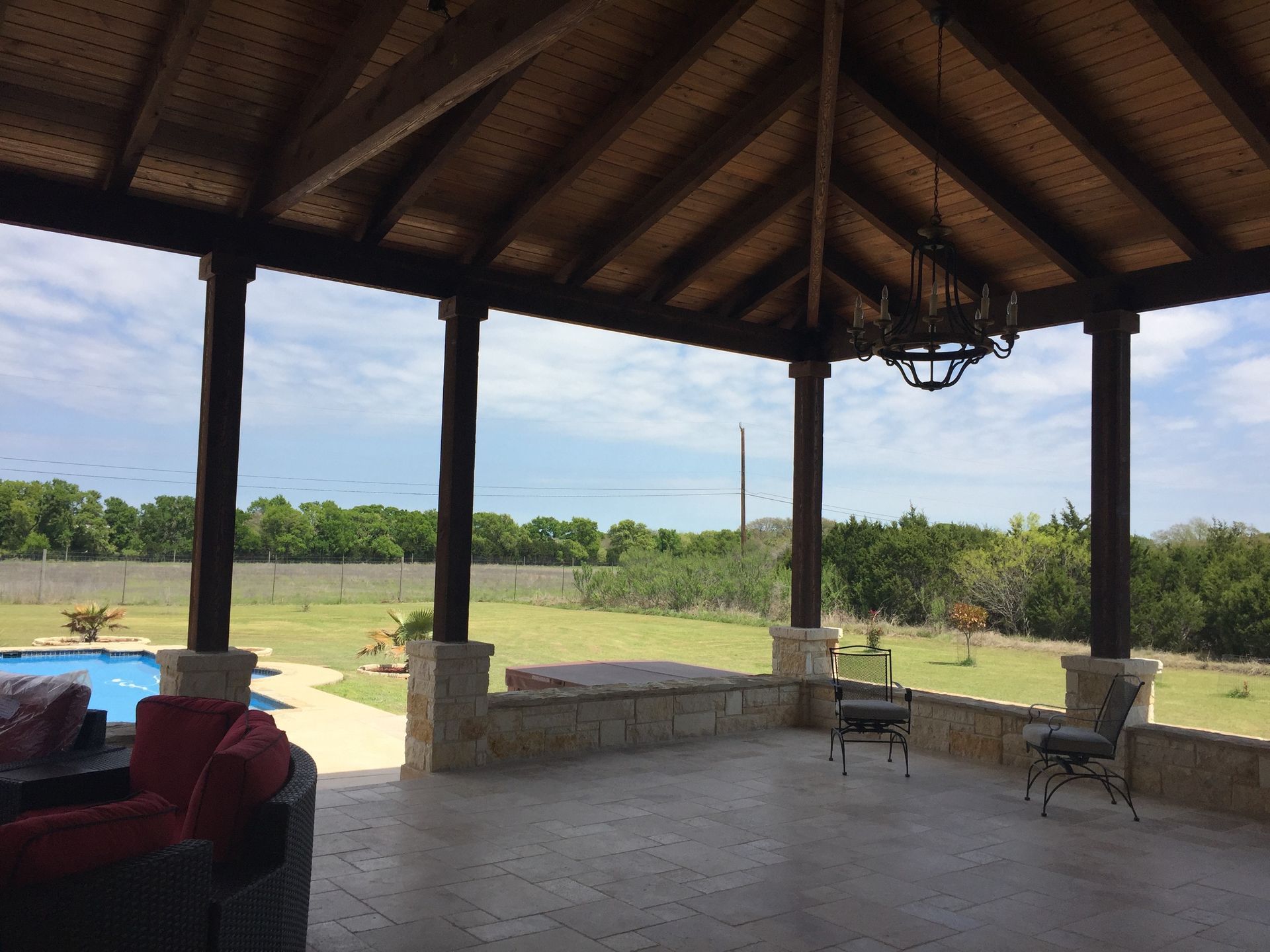 A large covered area with a chandelier hanging from the ceiling built by Fine Patio Design San Antonio TX