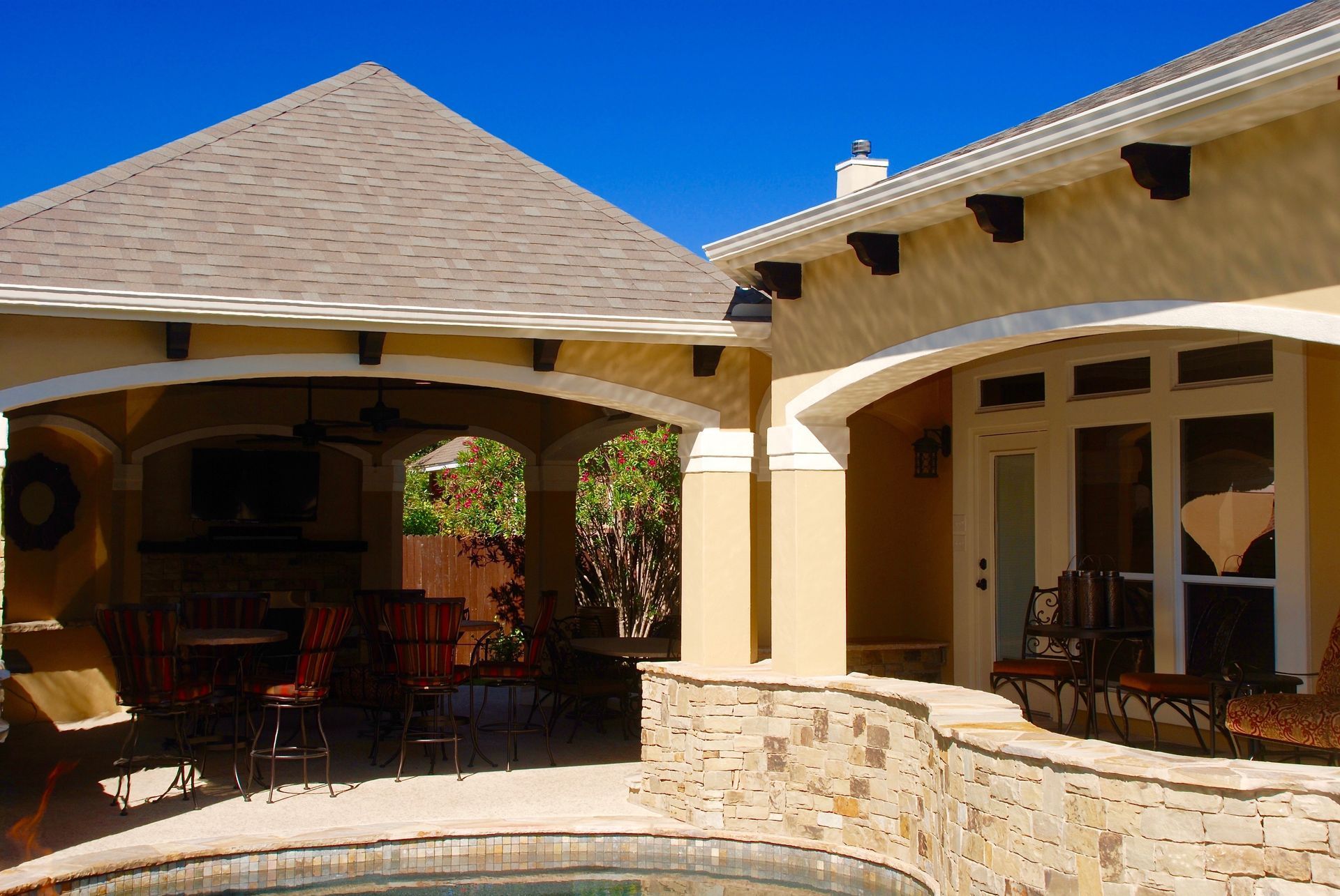 A house with a covered patio and a swimming pool built by Fine Patio Design San Antonio TX