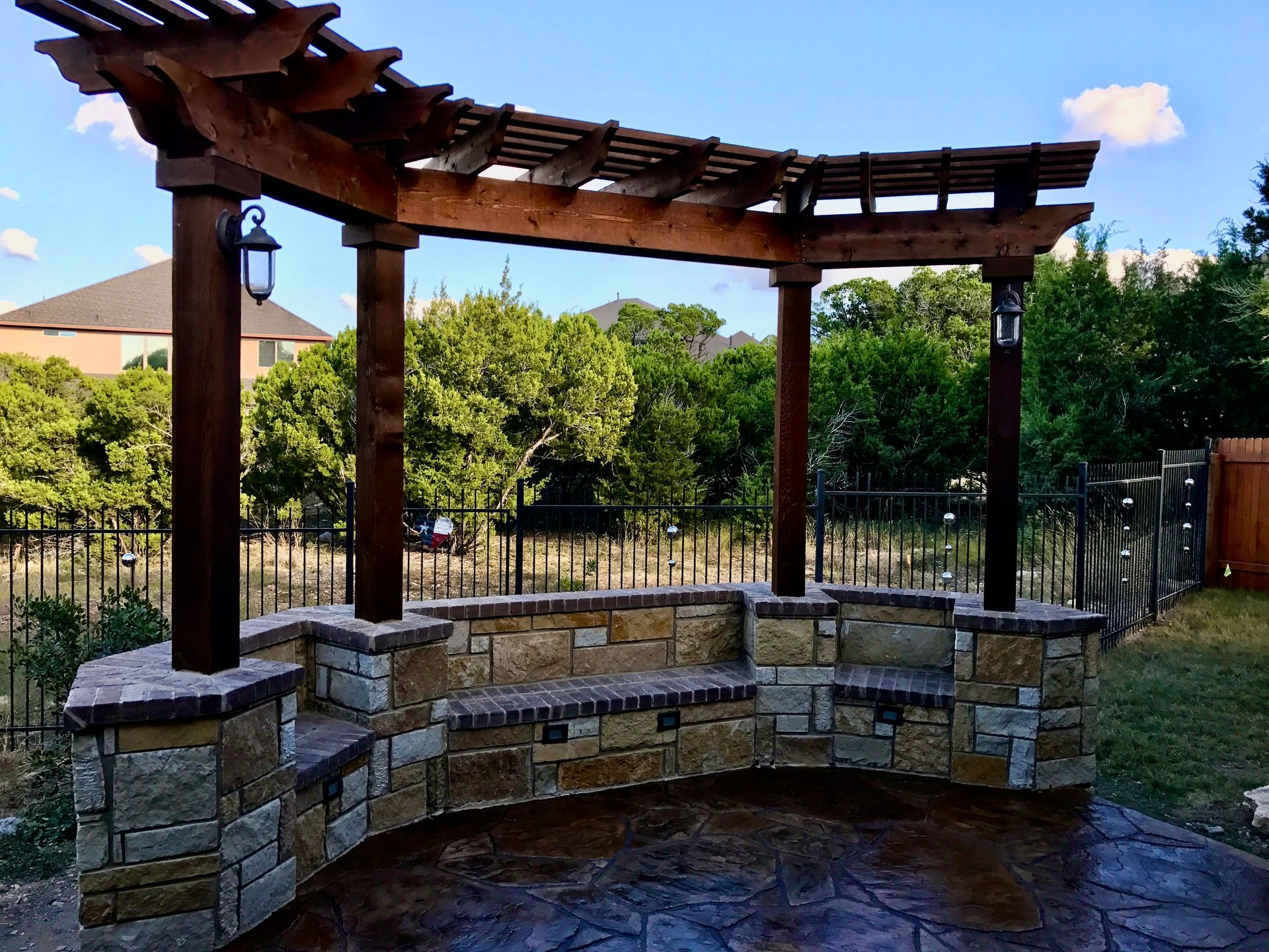 A wooden pergola with a stone bench underneath it built by Fine Patio Design San Antonio TX