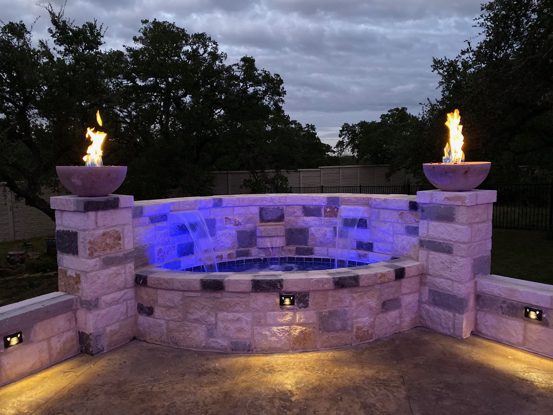 A fire pit is lit up with blue lights built by Fine Patio Design San Antonio TX